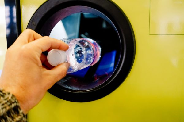 Some depositing a bottle in a container deposit service